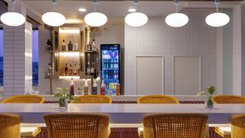 A bar area with wicker chairs, a counter with bottles, and a Coca-Cola vending machine.