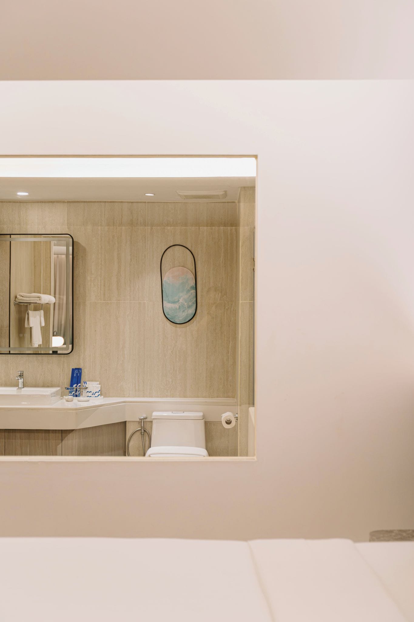 Un baño moderno con un espejo grande, un inodoro y un lavabo.