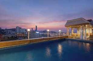 Una piscina en la azotea con vistas al horizonte de una ciudad al anochecer.