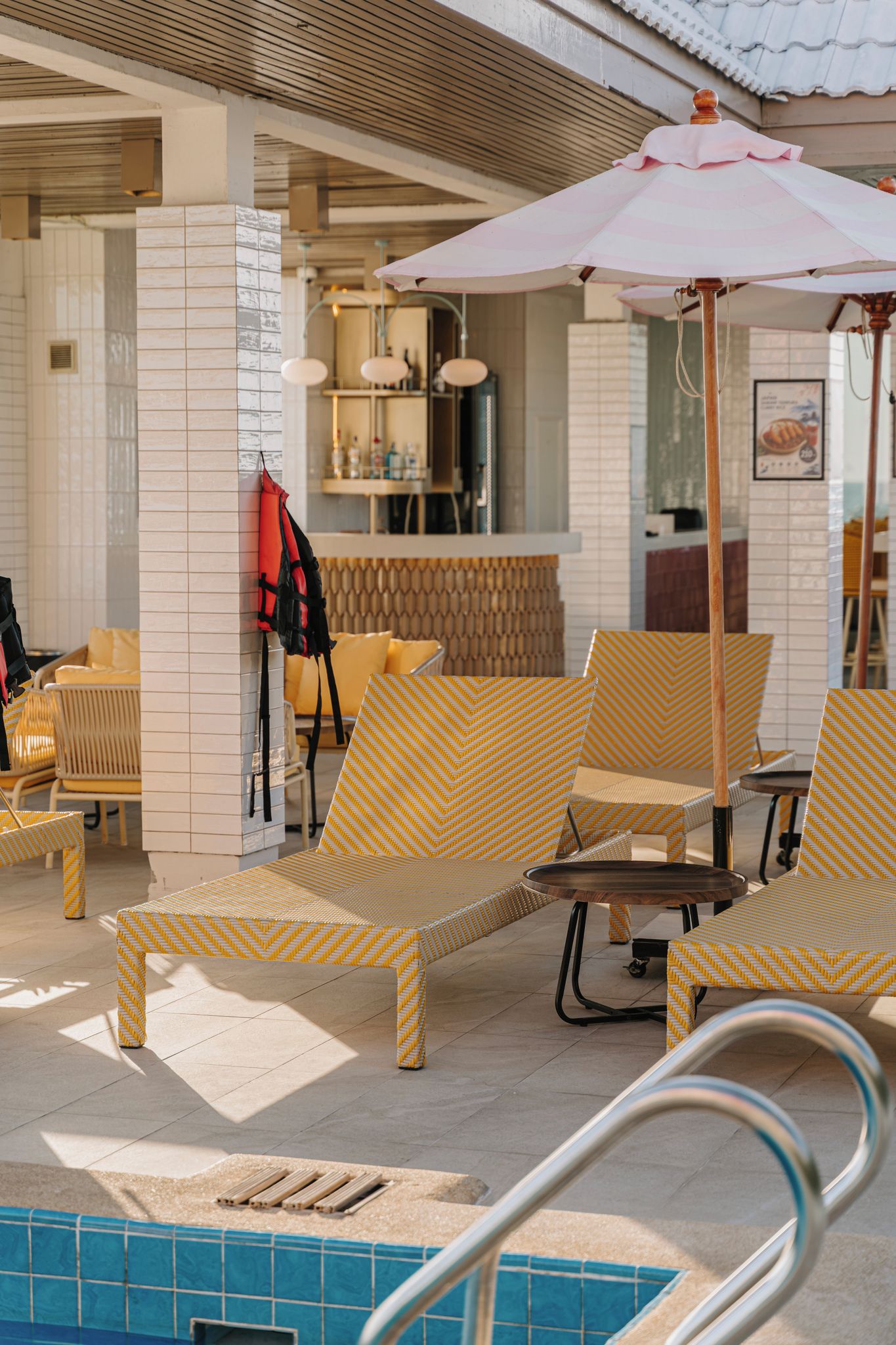 A poolside area with lounge chairs, a bar, and a pool.