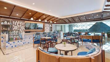 Een modern interieur met houten balken in het plafond, een bar met flessen en zitgedeeltes met banken en tafels.