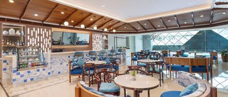 Ein modernes Interieur mit Holzbalkendecke, einer Bar mit Flaschen und Sitzgelegenheiten, darunter Sofas und Tische.