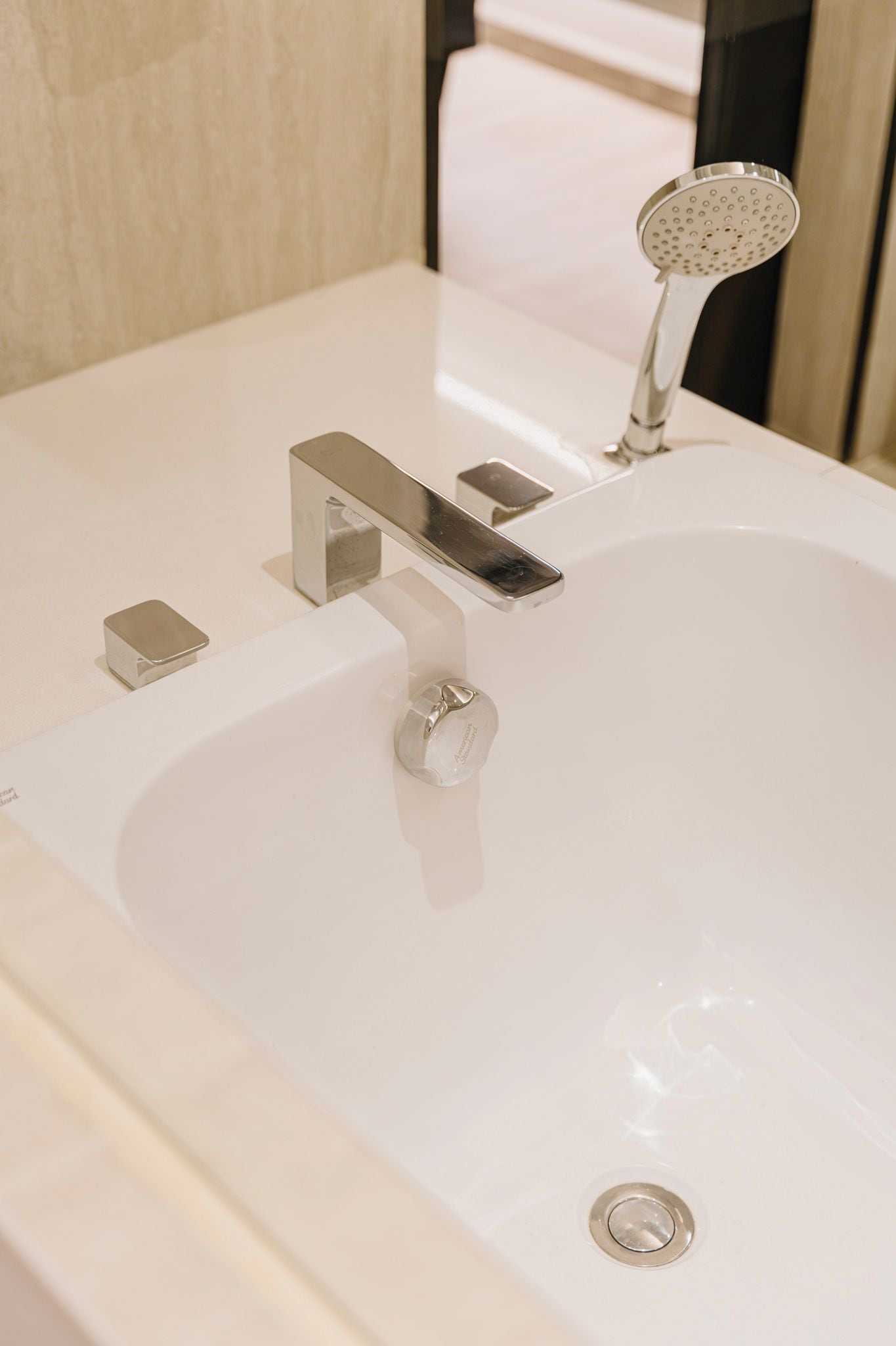 A modern bathroom with a white sink, a chrome faucet, and a handheld showerhead.