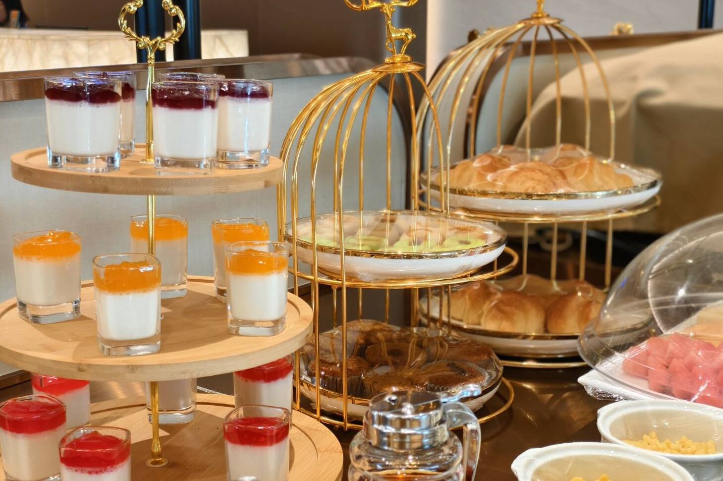 A dessert display with various types of desserts in glass containers and on a tiered stand.