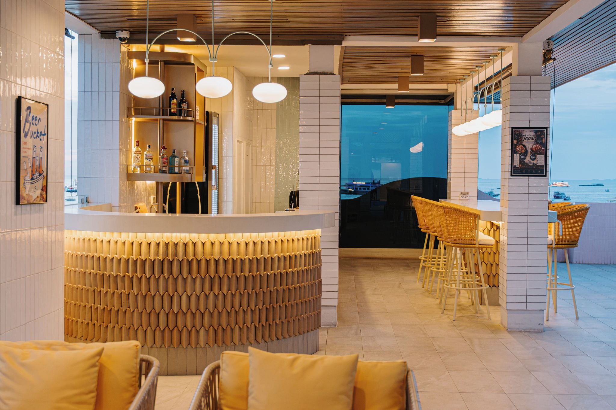 Un área de bar moderna con mostrador, asientos y vista al mar.