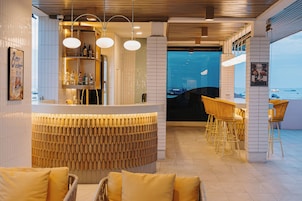 Un área de bar moderna con mostrador, asientos y vista al mar.