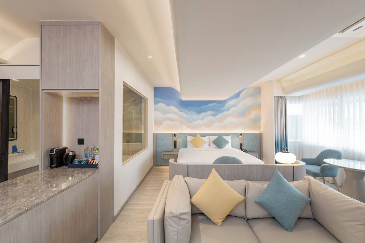 Een moderne hotelkamer met een bed, een sofa, een eethoek en een badkamer.