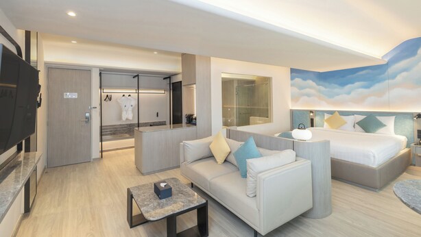 A modern hotel room with a sofa, a bed, a TV, a bathroom, and a large window. - Cloudotel Walking Street Pattaya  (Pattaya)