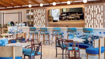 Un bar moderno con asientos azules, mesas de madera y una barra con espejo.