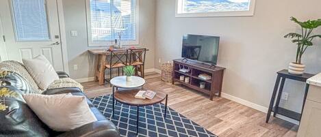 A living room with a sofa, coffee table, TV, and a view of the outdoors.