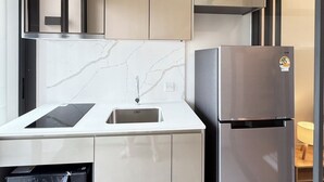 A modern kitchen with a built-in microwave, a stainless steel refrigerator, and a marble backsplash.