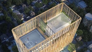 A high-rise building with a rooftop sports court and a glass facade.