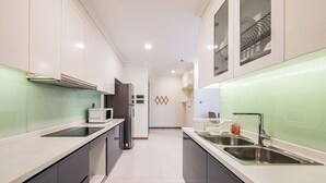 A modern kitchen with white cabinets, a stainless steel sink, and a microwave. - Apartment in Landmark-Vinhome.CTP by Yen (Ho Chi Minh City)