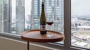 A table with a bottle of wine and a glass, set against a window with a cityscape view. - Apartment in Landmark-Vinhome.CTP by Yen (Ho Chi Minh City)