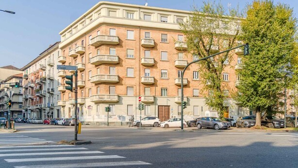 A multi-story building with balconies, a crosswalk, and parked cars. - GuestHost - La Mole Apartment with Balcony (Torino)