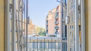 A view through a metal gate leading to a balcony with a clear sky and buildings in the background. - GuestHost - La Mole Apartment with Balcony (Torino)