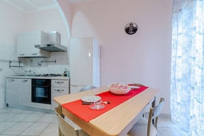 A modern kitchen with white cabinets, a gas stove, and a red tablecloth-covered dining table.