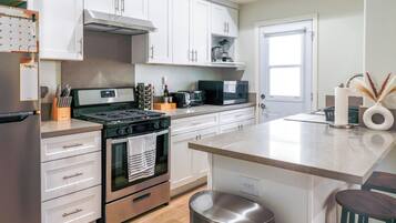 A modern kitchen with white cabinets, a stainless steel stove, a microwave, and a toaster.