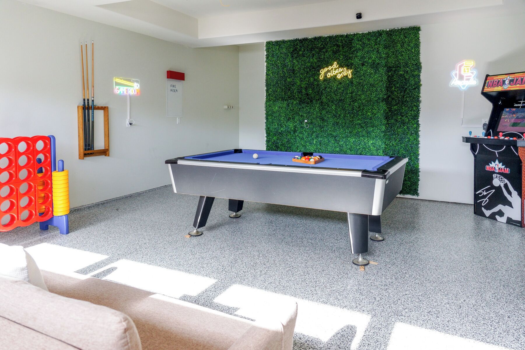 Ein Billardtisch in einem Raum mit grüner Wand, einem Rauchmelder und einer Spielautomat.