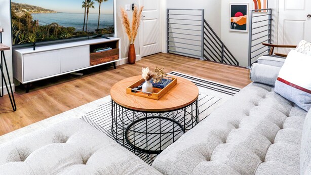 Un salon moderne avec un téléviseur à écran plat, une table basse ronde et un canapé capitonné.
