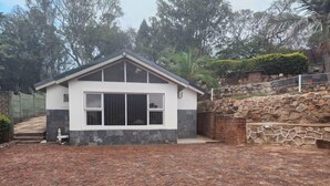 A modern two-story house with a stone wall and a paved driveway. - Room 1 of 8 Cozy Suites at The Hilltop Guesthouse (Harare)