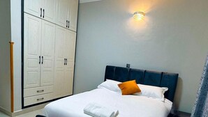 Una cama bien tendida con un cabecero oscuro, una almohada blanca y una toalla blanca doblada.