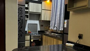 Una cocina moderna con encimera negra, armarios de madera y una campana extractora de acero inoxidable.