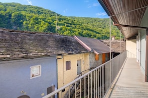 Ein Balkon mit Steinmauer und Blick auf einen bewaldeten Hügel.