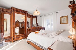Een slaapkamer met een groot houten bed, een kaptafel, een spiegel en een kroonluchter.