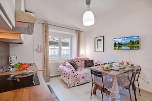 A modern kitchen with a built-in stove, a dining area with a table and chairs, and a large window with curtains. - Casa del Nildo near Mountain and Lake Mergozzo, Ornavasso, Italy (Ornavasso)