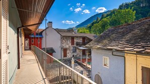 Un balcón con vistas a un pueblo de casas de piedra tradicionales, cielo despejado y una montaña al fondo.