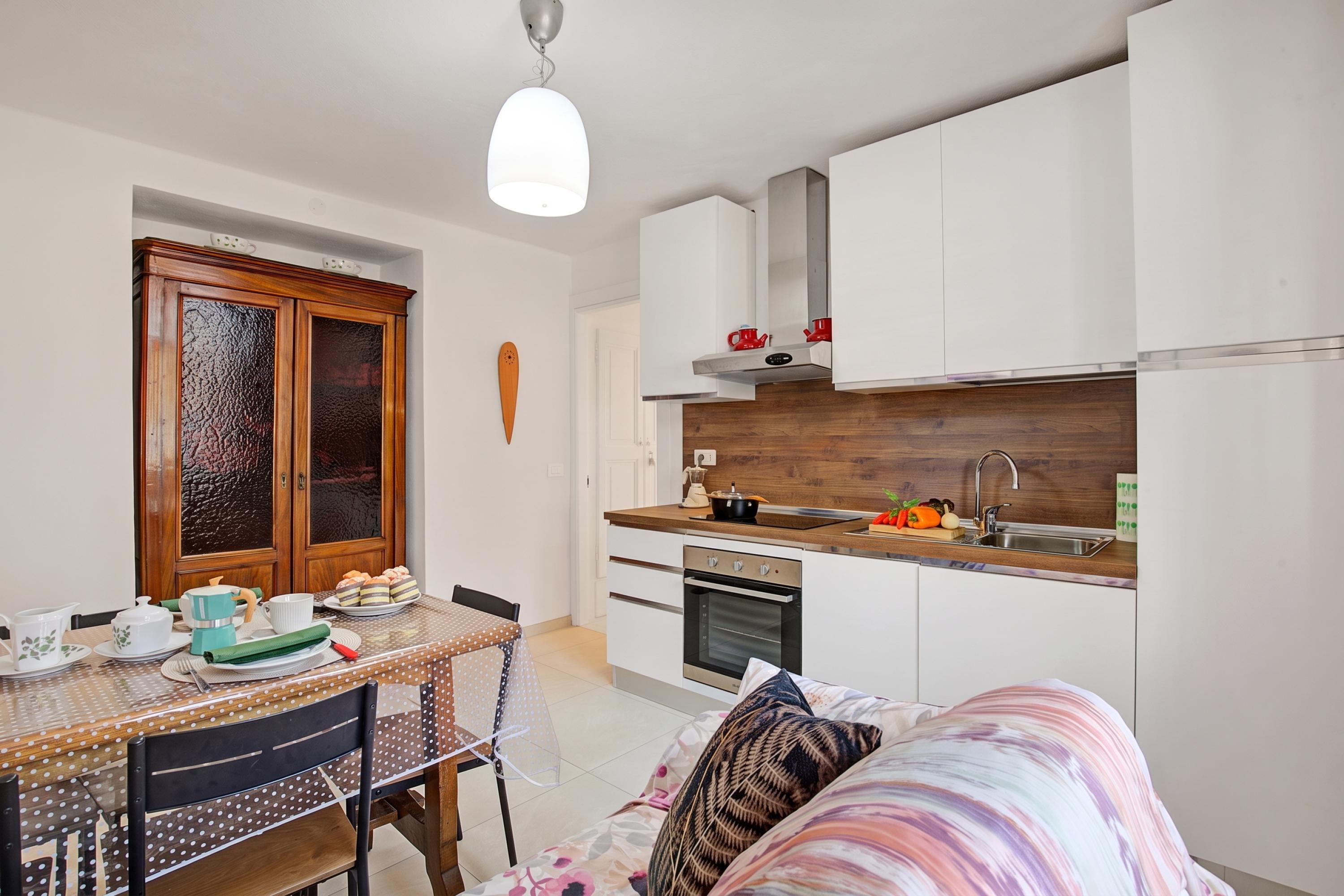 A compact kitchen with white cabinets, a wooden countertop, and a dining area with a table and chairs.