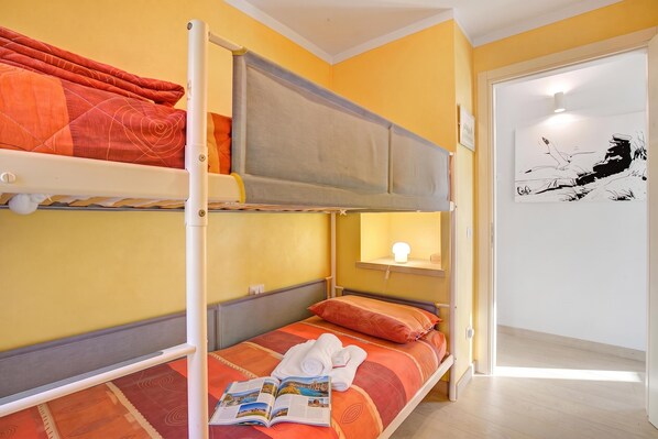 A bunk bed room with a reading light, a door with a black and white artwork, and a wooden floor. - Casa Adelaide, near Mountain and Lake Mergozzo, Ornavasso, Italy (Ornavasso)