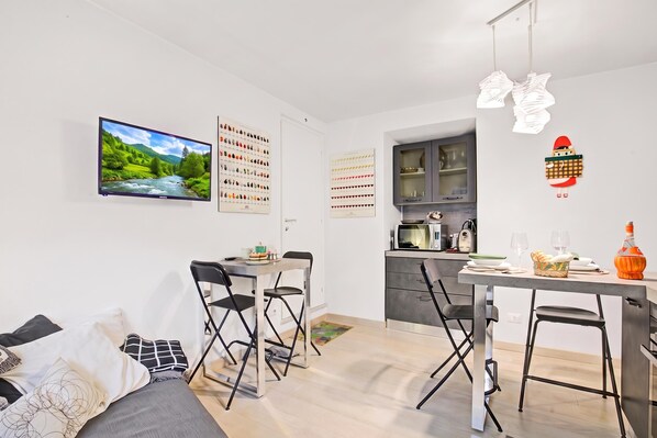 A modern kitchen with a microwave, toaster, and a small dining area with a table and chairs.
