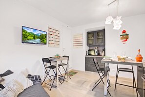 A modern kitchen with a microwave, toaster, and a small dining area with a table and chairs. - Casa Adelaide, near Mountain and Lake Mergozzo, Ornavasso, Italy (Ornavasso)