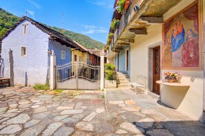 A narrow cobblestone street with traditional buildings, a gate, and a bench. - Casa Adelaide, near Mountain and Lake Mergozzo, Ornavasso, Italy (Ornavasso)