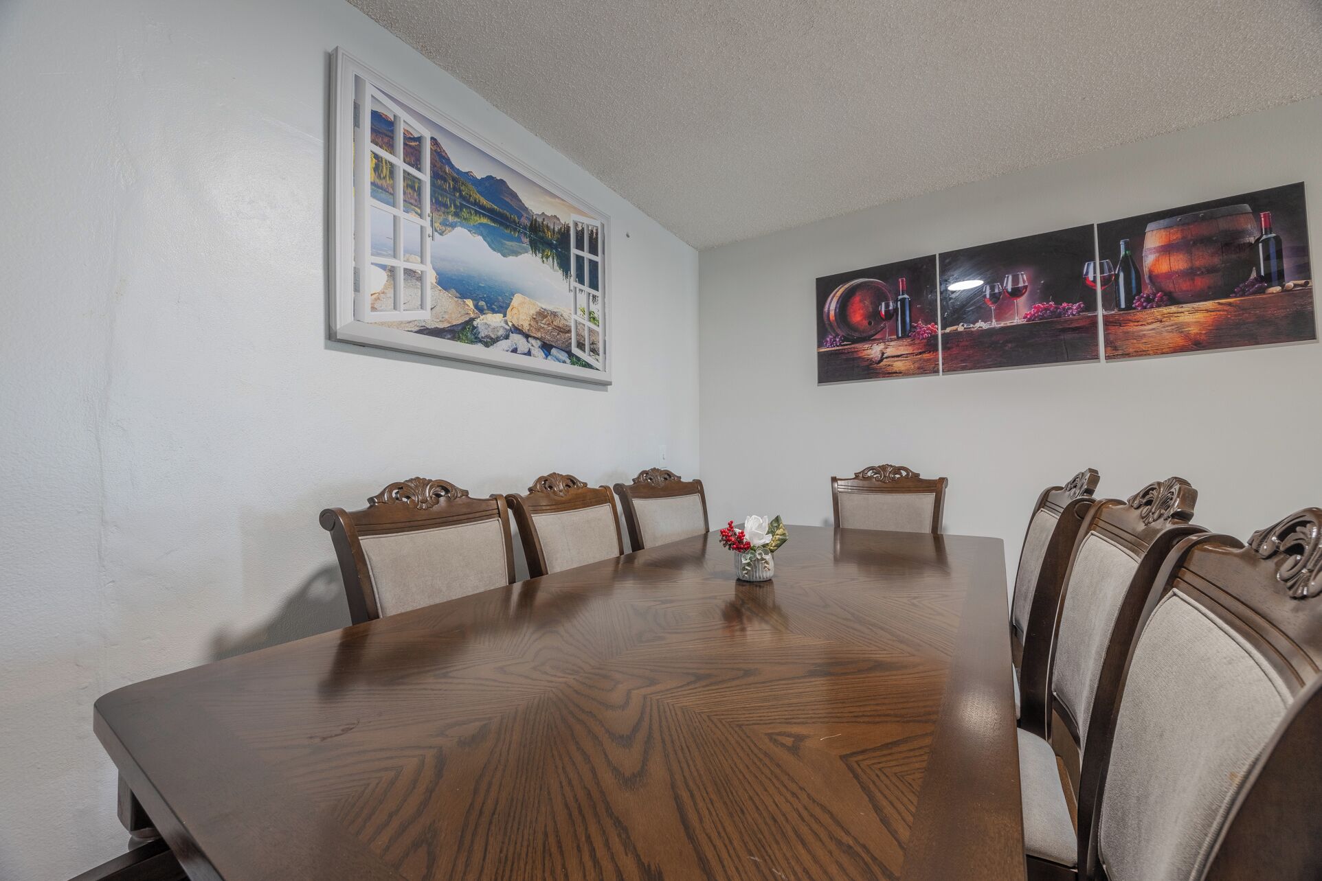 A dining room with a large wooden table, six chairs, and a window with a scenic view.