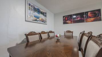 A dining room with a large wooden table, six chairs, and a window with a scenic view.