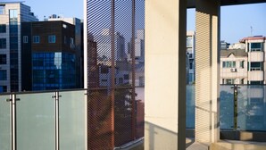 A balcony with a metal fence, concrete pillars, and a view of neighboring buildings. - Maison de Wave 3 (Seoul)