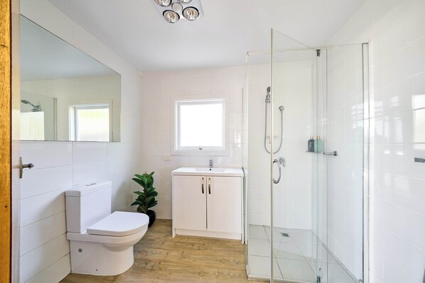 Un baño moderno con inodoro, lavabo y cabina de ducha de vidrio.