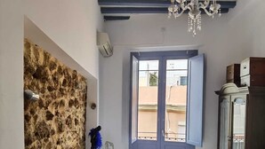 A bedroom with a bed, a chandelier, a stone wall, a window, and a wardrobe.