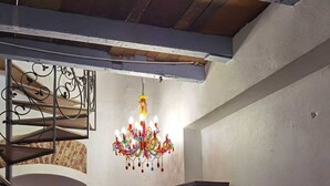 A dining area with a wooden table, chairs, a chandelier, and a bookshelf.