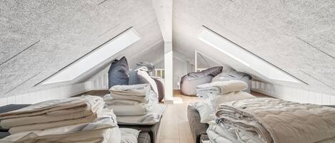 A loft bedroom with high ceilings, sloped ceilings, and skylights.
