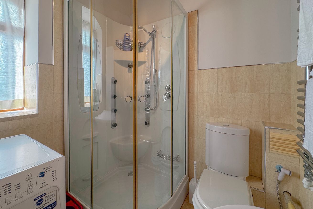 Ein Badezimmer mit einer Duschkabine, einer Toilette und einer Waschmaschine.