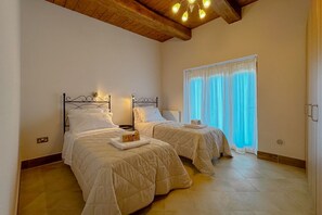 Une chambre avec deux lits, un plafond en bois, une fenêtre avec des rideaux et un luminaire.
