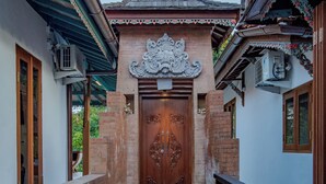 Un edificio tradizionale con una porta centrale in legno, una scala che conduce all'ingresso e un muro di mattoni alla sinistra.