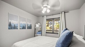 A bedroom with a bed, a ceiling fan, a window with curtains, and three framed pictures on the wall. - Pet Friendly Flagstaff home Mountain Views &Grill (Flagstaff)