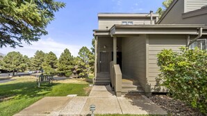 A residential building with a covered porch, a front door, and a small front yard with a bench and trees. - Pet Friendly Flagstaff home Mountain Views &Grill (Flagstaff)