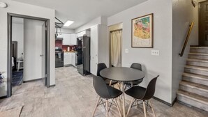 A modern kitchen with white cabinets, a dining area with a round table and four chairs, and a staircase with a wooden handrail. - Pet Friendly Flagstaff home Mountain Views &Grill (Flagstaff)