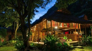A wooden building with a reception area and a bar, surrounded by lush greenery and trees. - Thai House Pu Luong (Co Lung)